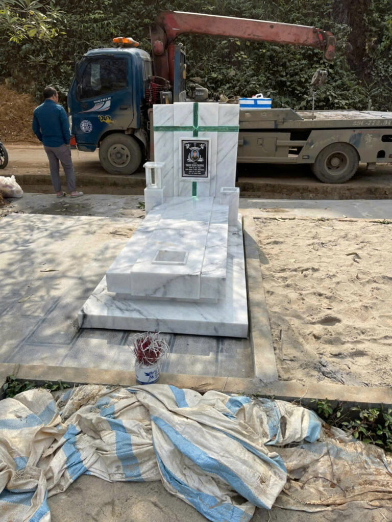 Mộ đá trắng đang được lắp đặt tại nghĩa trang thành phố Yên Bái, có xe cẩu hỗ trợ