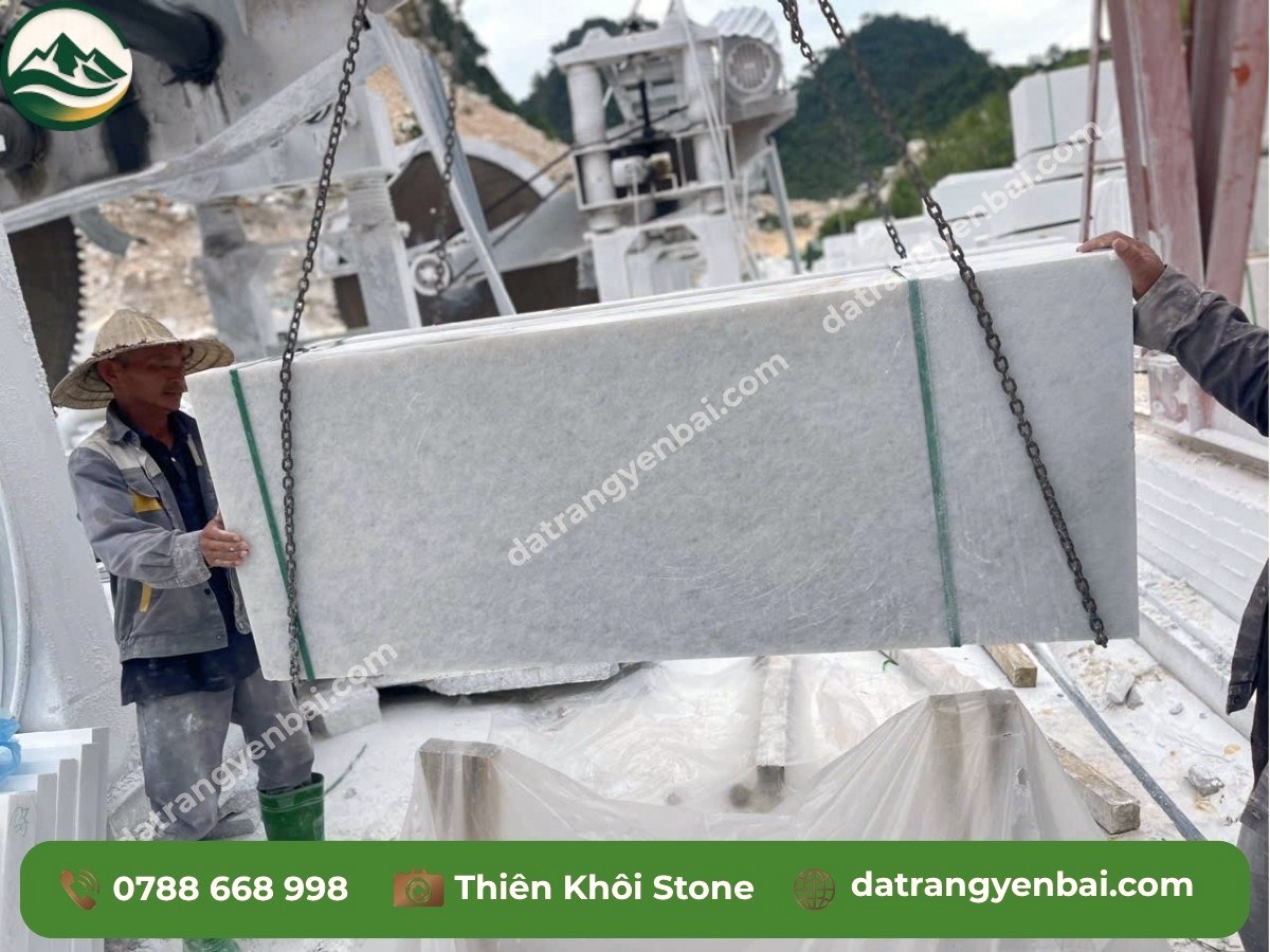 Công nhân dùng cẩu xích nâng tấm slab đá trắng Yên Bái khổ lớn tại khu chế biến đá